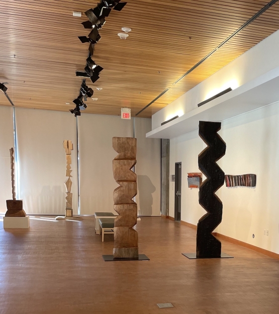 gallery with wooden floors, and 2 tall carved wooden sculptures